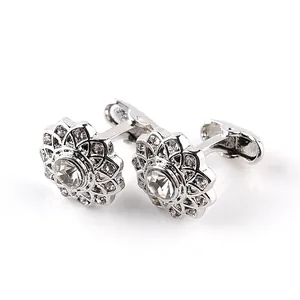 Detailed macro view of silver-toned circular cufflinks with intricate diamond-set floral patterns