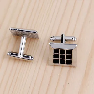 Détail macro de boutons de manchette carrés argentés avec motif de grille noire sur bois