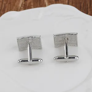 Close-up of rectangular silver cufflinks with textured grid surface and bullet back closure