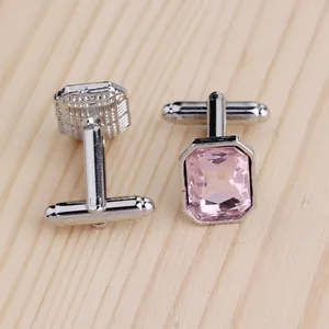 Klassische Herren-Manschettenknöpfe mit rosa Kristall im Smaragdschliff auf hellem Holz