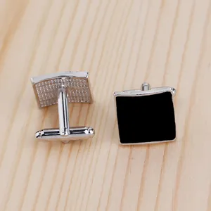 Detailed macro view of square silver cufflinks with black enamel inlay and T-bar clasp