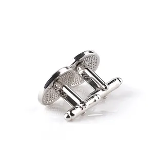 Close-up of circular two-tone men's cufflinks with polished silver finish and grid texture