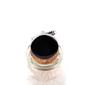 Close-up of elegant round silver cufflinks with black polished enamel on a cork base
