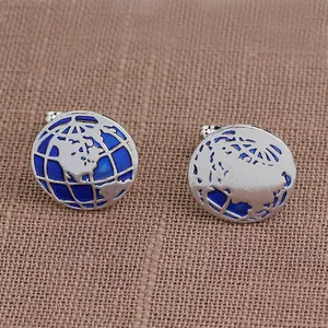 Silver round cufflinks with blue enamel world map design on brown linen background