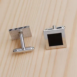 Detailed view of square silver cufflinks with black enamel inlay and T-shaped closures