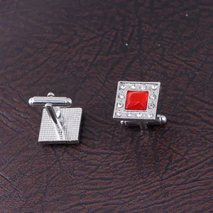 Detail of square silver cufflinks featuring a large red gemstone and sparkling accents