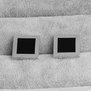 Macro shot of square silver-toned cufflinks with black enamel inlay in a velvet box