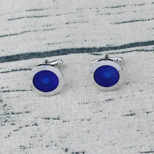 Detailed macro view of silver-rimmed blue enamel cufflinks with radial sunburst texture