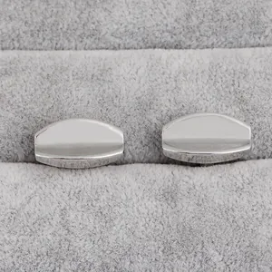 Pair of polished silver geometric capsule cufflinks displayed on a grey velvet background