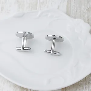 Classic silver oval cufflinks with textured grid pattern on elegant white porcelain