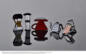 Macro shot of 5 coffee enamel pins including Chemex and French press on black mirror