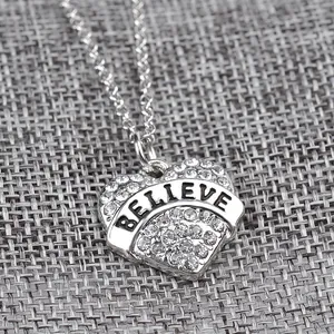 Vista macro di una collana con ciondolo a cuore con incisione BELIEVE e strass lucidi