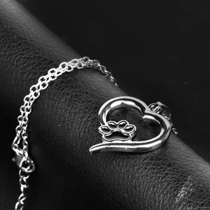 Hollow heart necklace with pet paw print pendant on elegant black leather background