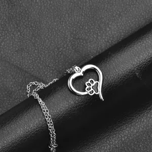 Macro shot of silver pet paw necklace with hollow heart pendant on black leather