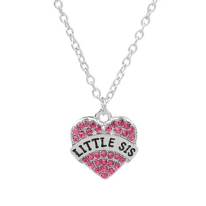 Close-up of heart pendant with pink rhinestones and LITTLE SIS engraving on silver chain