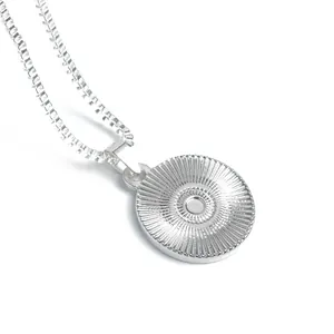 Dettaglio di un ciondolo tondo argento con trama radiale su una collana a scatolina