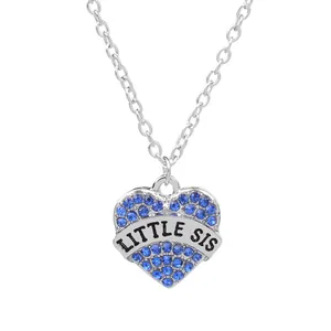 Close-up of heart pendant with blue rhinestones and LITTLE SIS engraving on silver chain