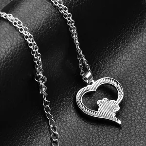 Detailed close-up of hollow heart pendant with silver pet dog paw print on black leather