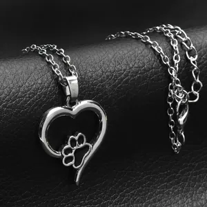Polished silver heart pendant necklace with a dog paw print on black leather background