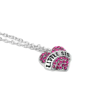 Close-up of heart pendant necklace with Little Sis engraving and pink rhinestones