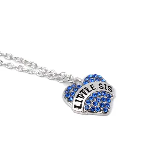 Close-up of heart pendant with blue rhinestones and Little Sis engraving details