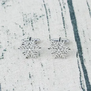 Silver snowflake cufflinks with sparkling rhinestones on a rustic wooden background