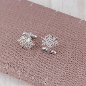 Close-up of silver snowflake cufflinks with sparkling crystals on textured fabric
