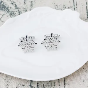Silberne Schneeflocken-Manschettenknöpfe mit Diamanten auf weißem Dekotablett