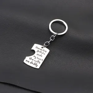 Macro shot of silver puzzle piece keychain with daddy quote on black leather background