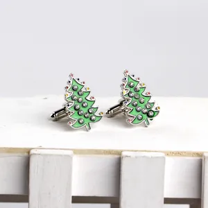 Close-up of green Christmas tree cufflinks with rhinestones on a white wooden stand