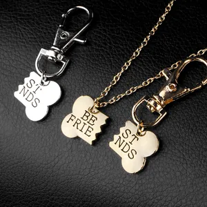 Macro detail of gold and silver bone-shaped puzzle pendants with Best Friends engraving