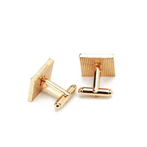 Detail of square gold cufflinks featuring fine grid texture and T-bar swivel closure