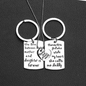 Polished stainless steel family keychain and heart necklace set on black leather background
