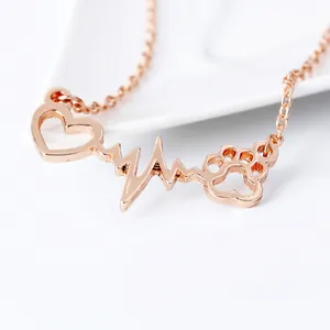 Macro shot of rose gold heart and paw print pendant with heartbeat line detail