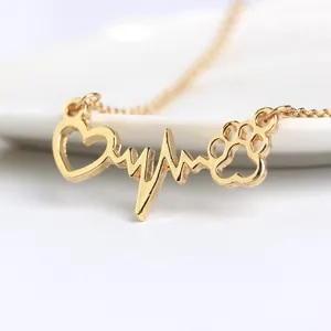 Close-up of golden necklace with integrated heart, heartbeat line and paw print pendant