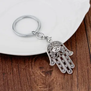 Detailed view of silver Hamsa Hand keychain with Evil Eye on a white ceramic plate