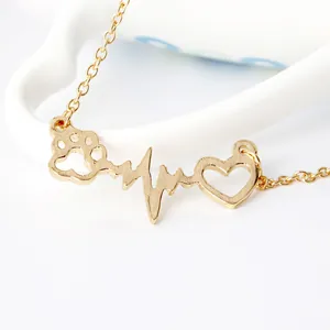 Golden heart and dog paw print pendant necklace with heartbeat design on white ceramic
