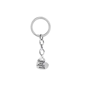 Close-up of heart keychain engraved with Daddy's girl Mama's world text on silver metal