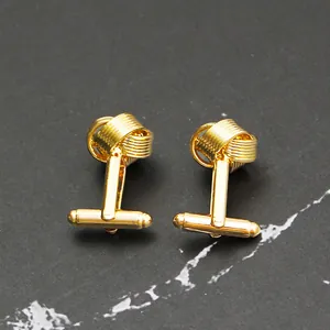 Détail macro de boutons de manchette nœud doré avec finition polie et fermoir en T