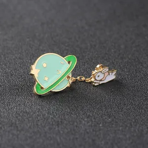 Detail of enamel planet brooch with gold star patterns and hanging white rabbit charm