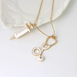 Détail du collier avec pendentifs seringue dorée et stéthoscope sur une chaîne fine