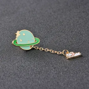 Detailed enamel pin showing a green planet and a sleeping white rabbit with gold chains
