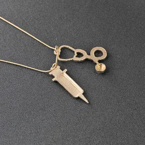 Collier doré avec pendentifs stéthoscope et seringue pour médecins sur fond texturé