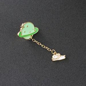 Detailed view of enamel brooch featuring a cartoon planet linked to a white rabbit