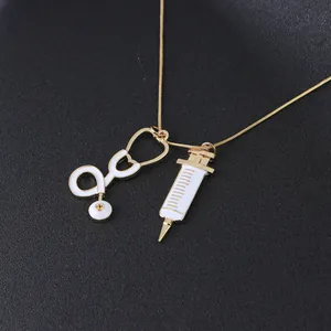 Détail d'un collier médical doré avec des pendentifs stéthoscope et seringue en émail