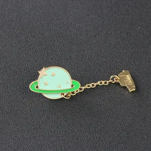 Detailed macro view of mint green cartoon planet enamel brooch with golden chain