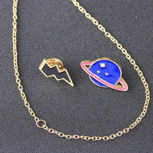 Detail of blue planet and black lightning enamel pins with gold trim and chain