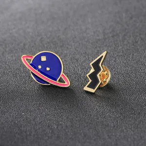 Enamel pins set with dark blue planet and black lightning bolt in gold finish