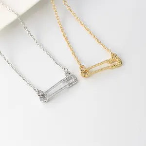 Détail macro de pendentifs épingles à nourrice dorés et argentés avec accents diamant