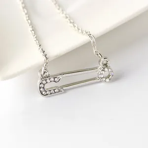 Vue détaillée du collier pendentif épingle à nourrice avec cristaux sur céramique blanche